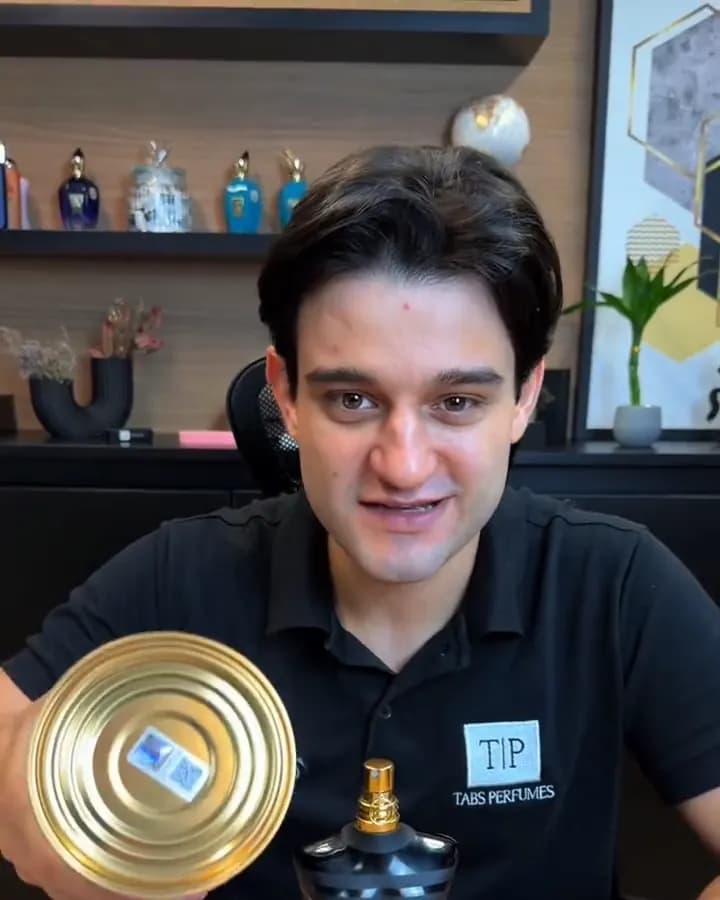 Gabriel mostra a embalagem do perfume original com o selo da ADIPEC na tampa, ao lado do frasco