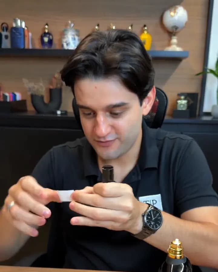 Gabriel cola a etiqueta de vinil com a foto e o nome do perfume no decant