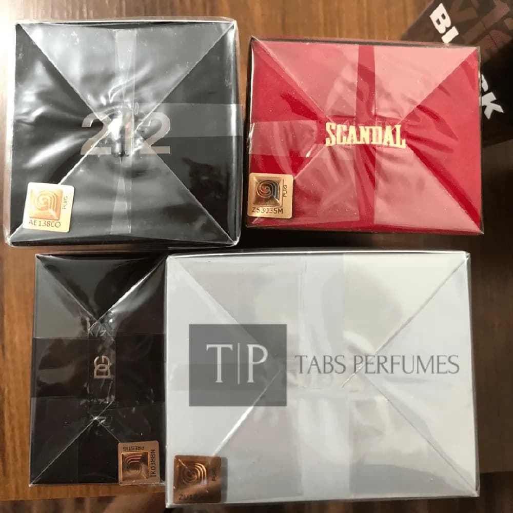 Quatro caixas de perfume lacradas no plástico, cada uma com o selo holográfico da ADIPEC e seu código
