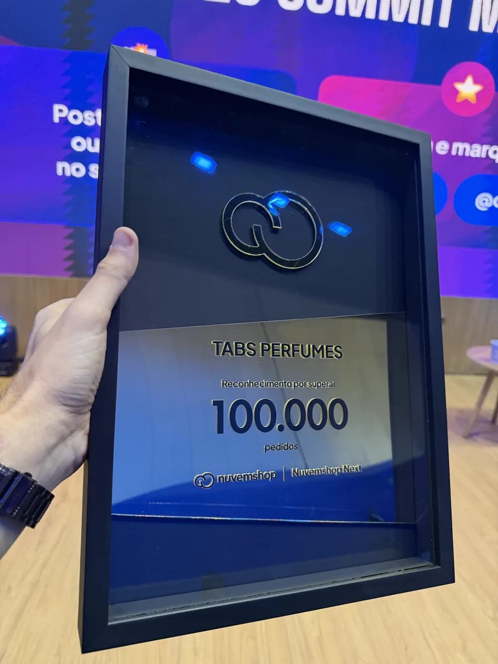 Placa da Nuvemshop entregue à Tabs Perfumes pelo reconhecimento por superar 100.000 pedidos